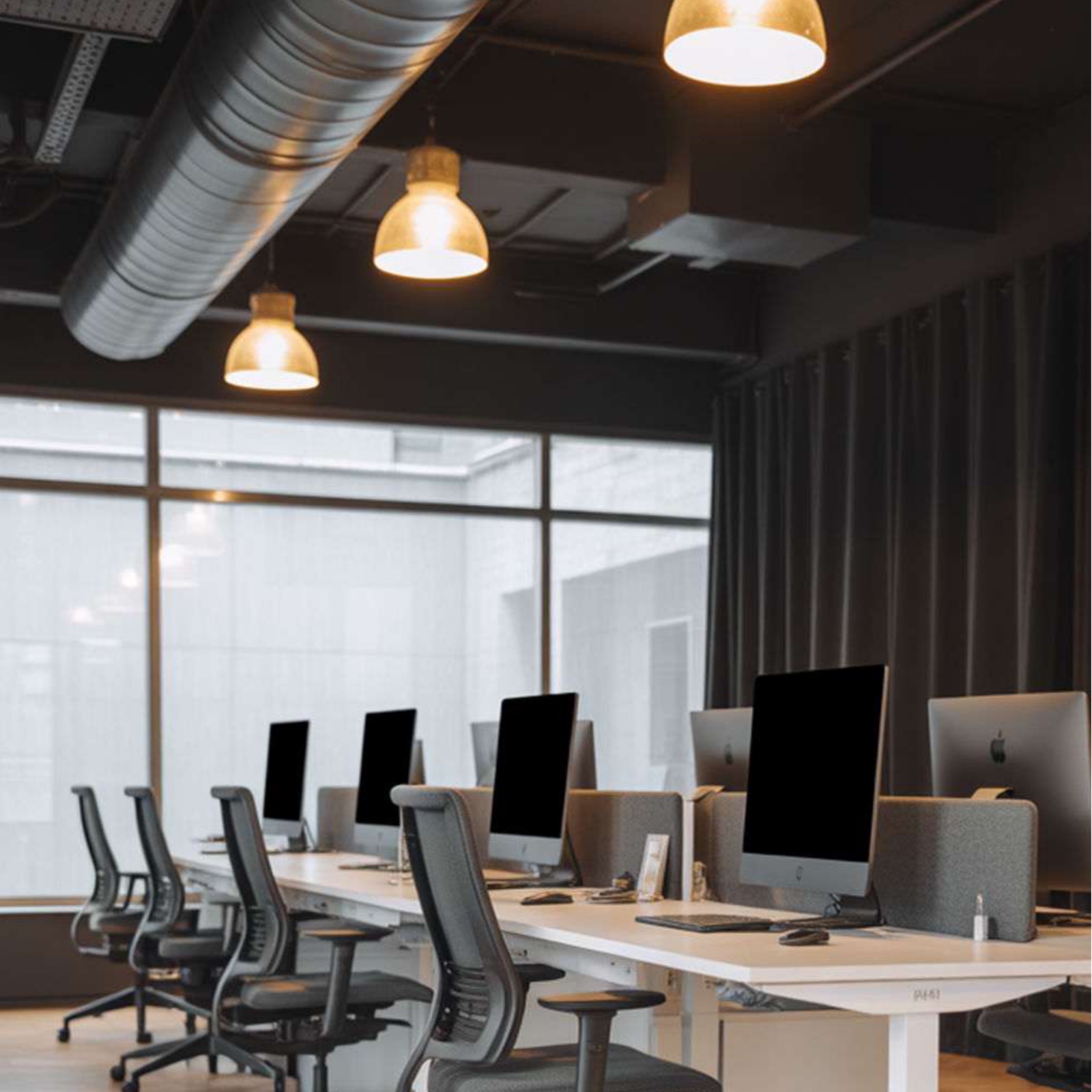 Open space avec bench desks éclairés par suspensions dôme dorées