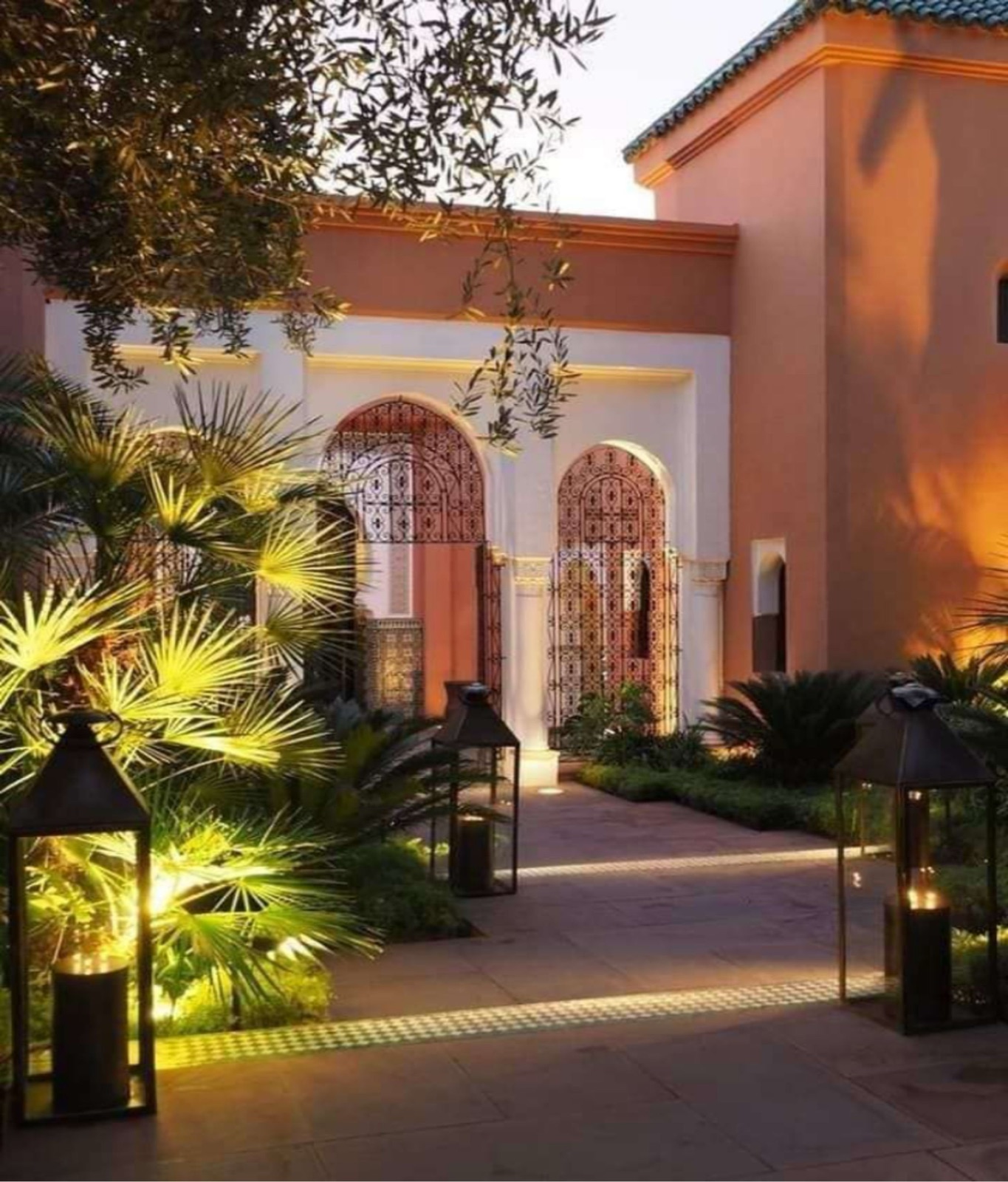 Entrée de riad avec grilles en ferronnerie et lanternes posées éclairant l'allée