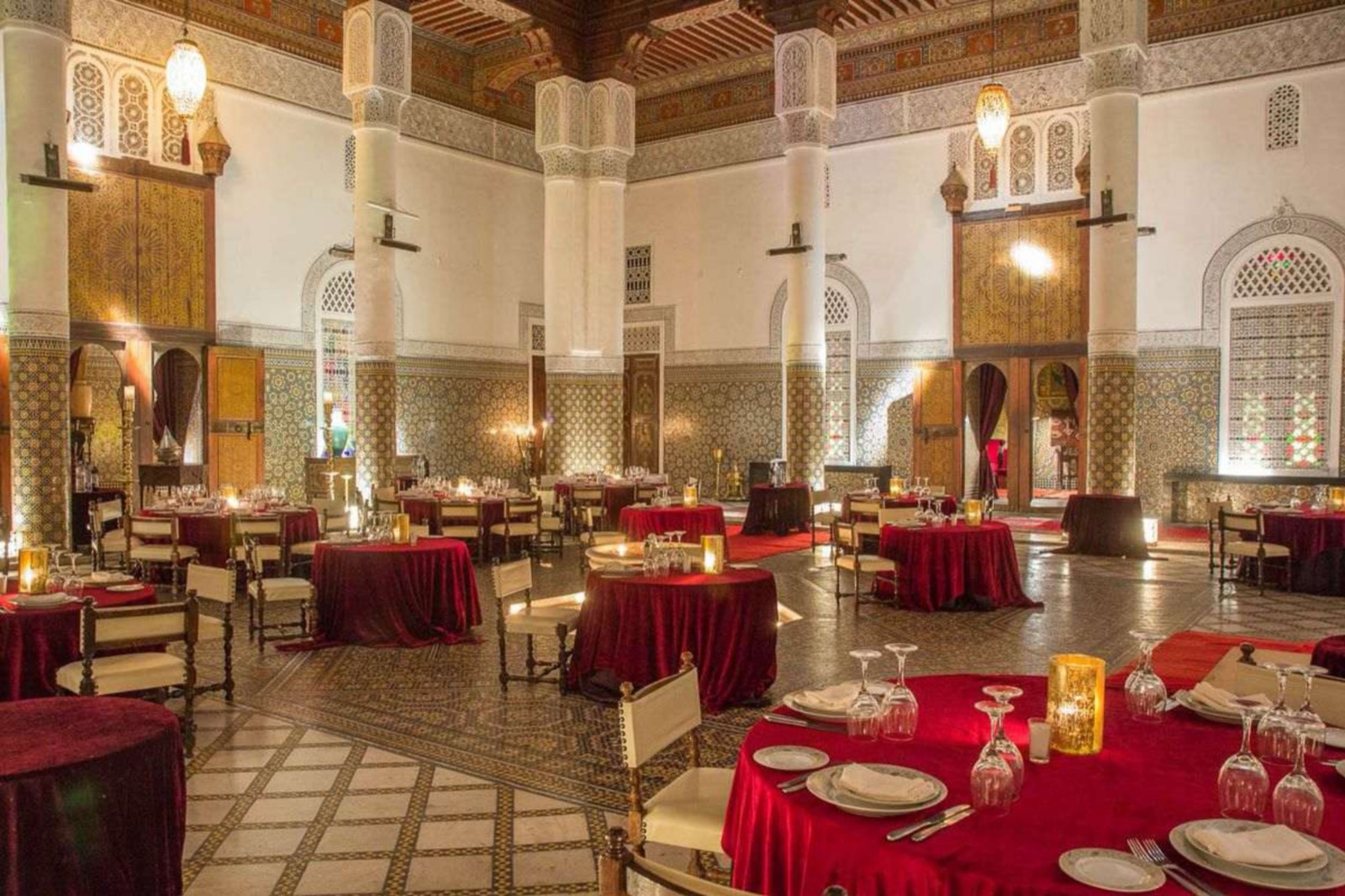 Salle de banquet de riad illuminée par bougeoirs et lustres ajourés